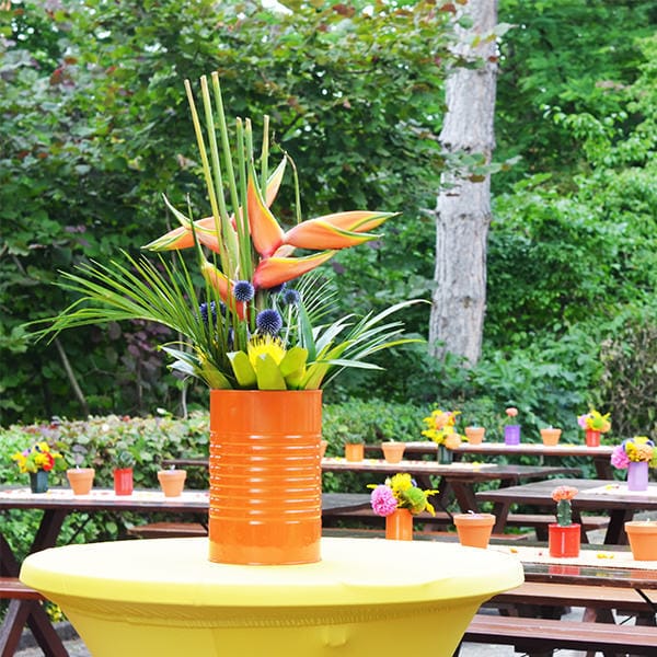 Eine gelbe Tischdekoration mit einem Blumenarrangement darauf.