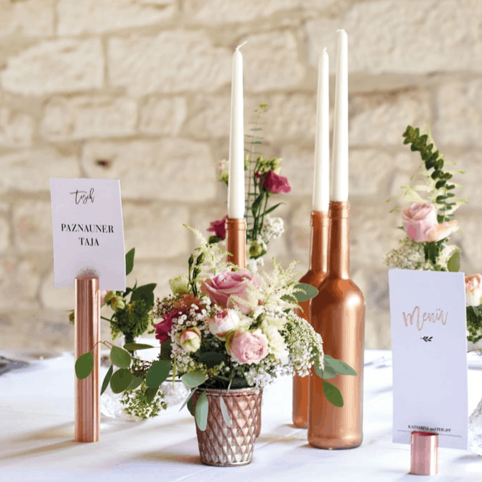 Eine Tischdekoration mit Kupferkerzenhaltern und Blumen in der Galerie für Hochzeiten.