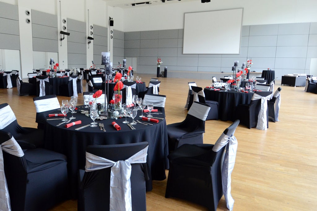 Dekoration Firmenveranstaltung schwarze Tischdecken mieten rote Akzente mit Blumen Rauers Festhalle Neckarsulm 4
