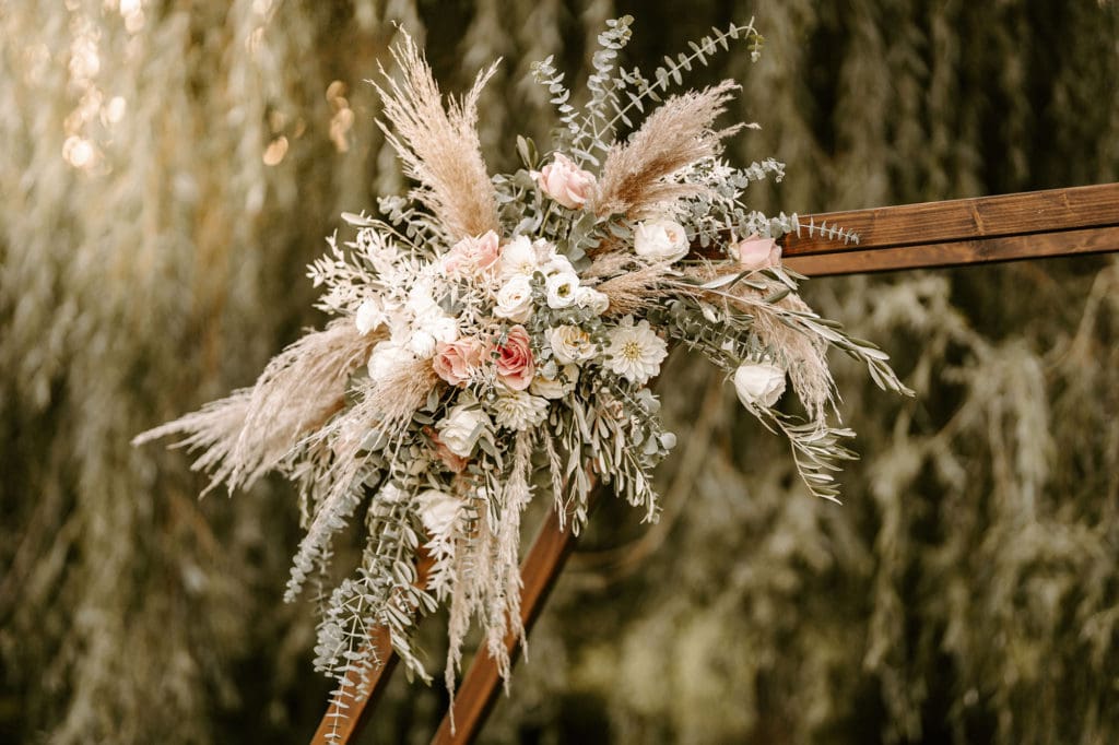 Ein Hochzeitsbogen, dekoriert mit getrockneten Gräsern und Blumen.