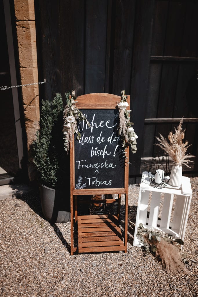 Dekoration_Hochzeit_Schloss_Liebenstein_Eingang_willkommen_schild_tafel_weinkiste_natur_blush_rose_gruen_rosen_pampasgras_Trockenblumen_eukalyptus