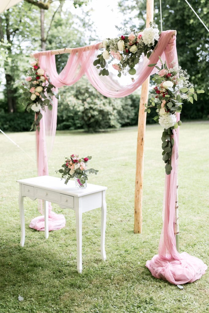 Dekoration_Hochzeit_Schlosshotel_Friedrichsruhe_FreieTrauung_Traubogen_Birke_Blumen_Tuch_Trautisch_Altar_rosa