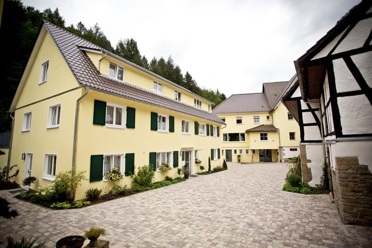Traditionelle gelb gestrichene Gebäude mit grünen Fensterläden im ländlichen Innenhof der Siegelsbacher Mühle.