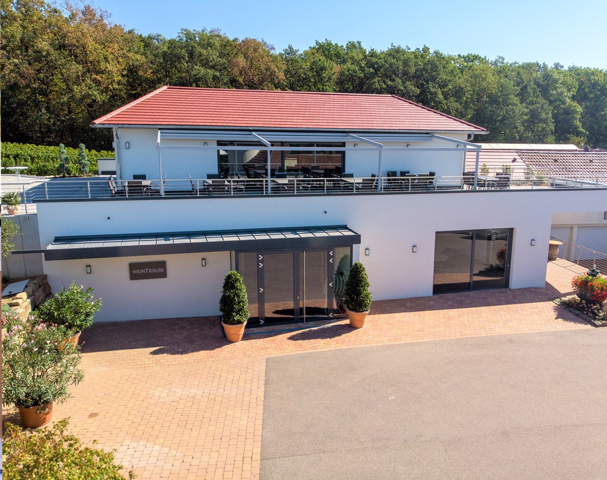 Modernes zweistöckiges Haus mit rotem Ziegeldach, Balkon, angebauter Garage und Teil des Anwesens des Familienweinguts Kurz-Wagner.