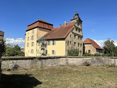 Historisches gelbes Schloss Heuchlingen mit Turm unter blauem Himmel.