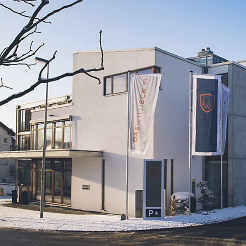 Modernes zweistöckiges Gebäude mit draußen hängenden Bannern an einem sonnigen Tag mit Schnee auf dem Boden, gelegen in bester Stadtlage.