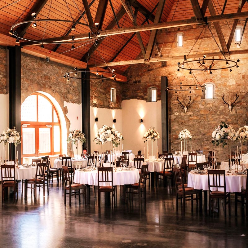 Ein elegant eingerichteter Hochzeitsempfangssaal mit dekorierten Tischen, rustikalen Kronleuchtern und erstklassigen Standorten.
