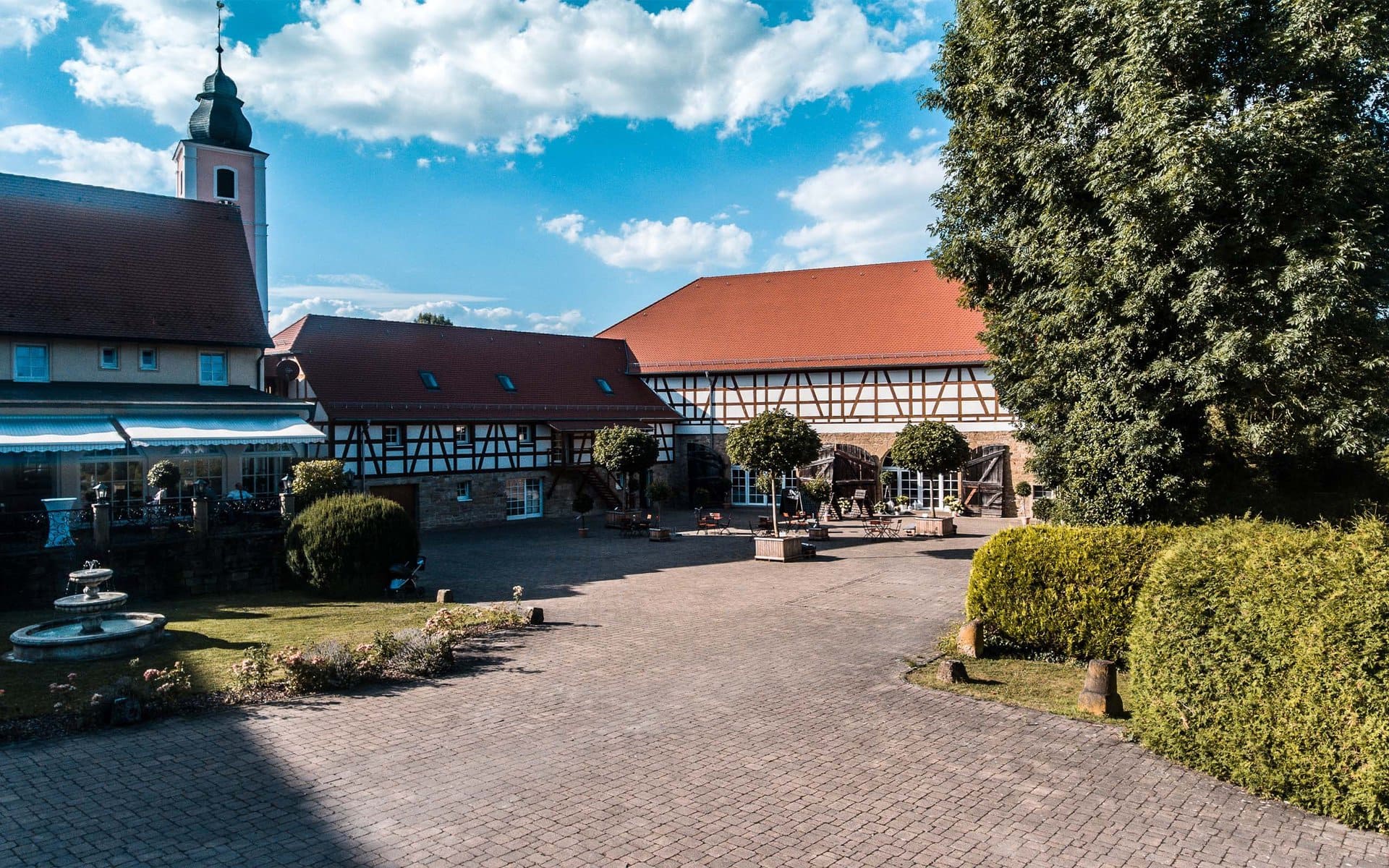 Traditionelle Fachwerkhäuser und eine Kirche mit Innenhof unter einem strahlend blauen Himmel auf Schloss Heinsheim.