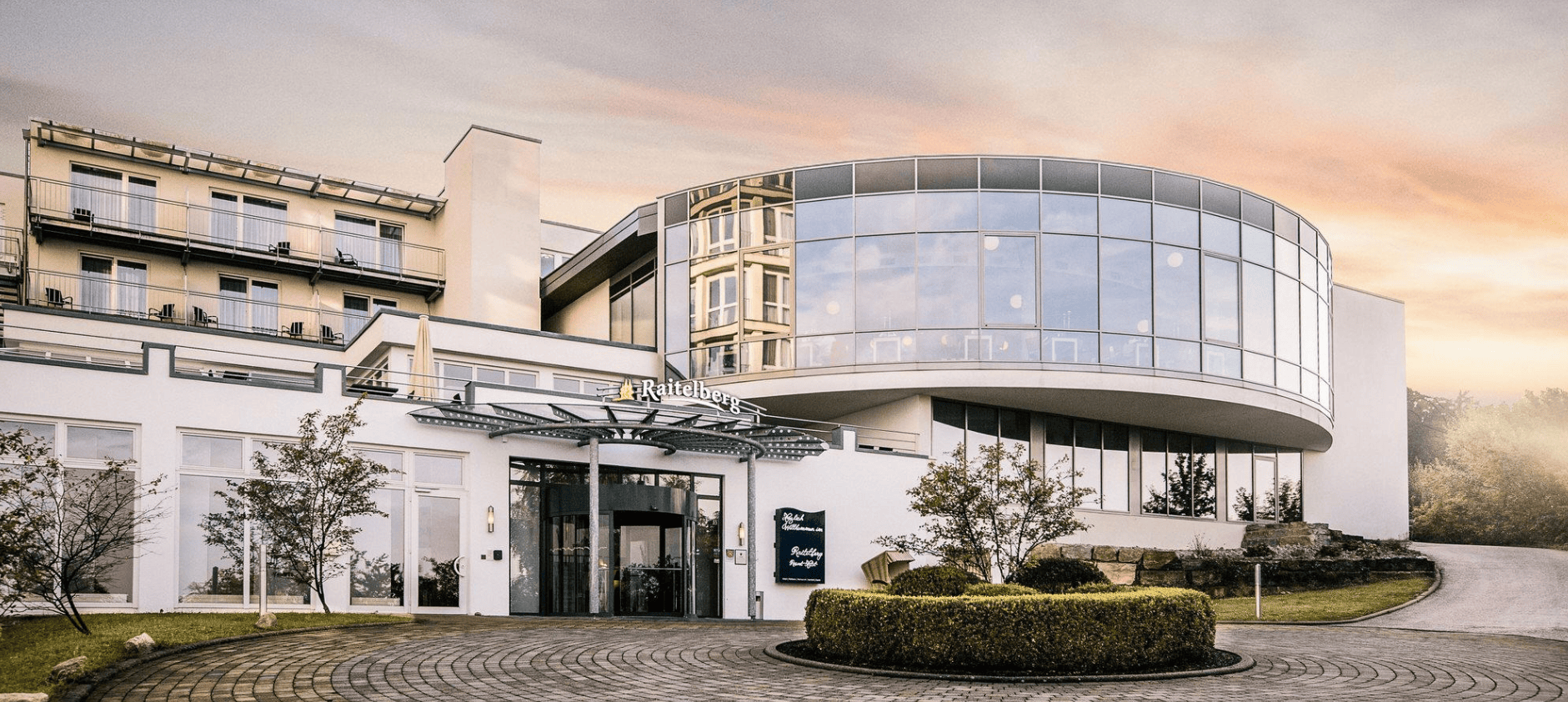 Modernes Hotel Raitelberg mit Glasfassade in der Dämmerung.