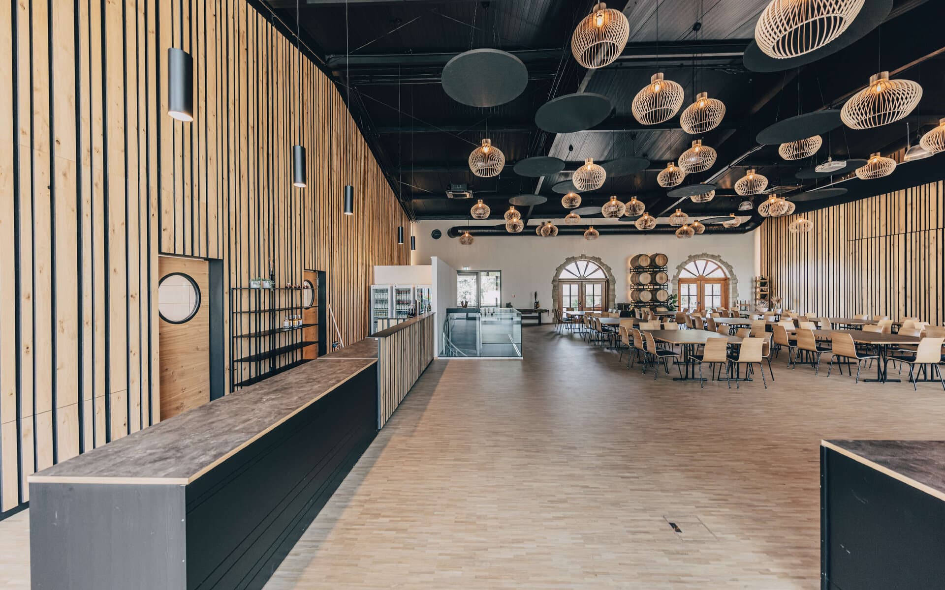 Modernes Restaurantinterieur mit Holzwänden, Pendelbeleuchtung und leeren Tischen im Landgut Steng am Rotenberg.