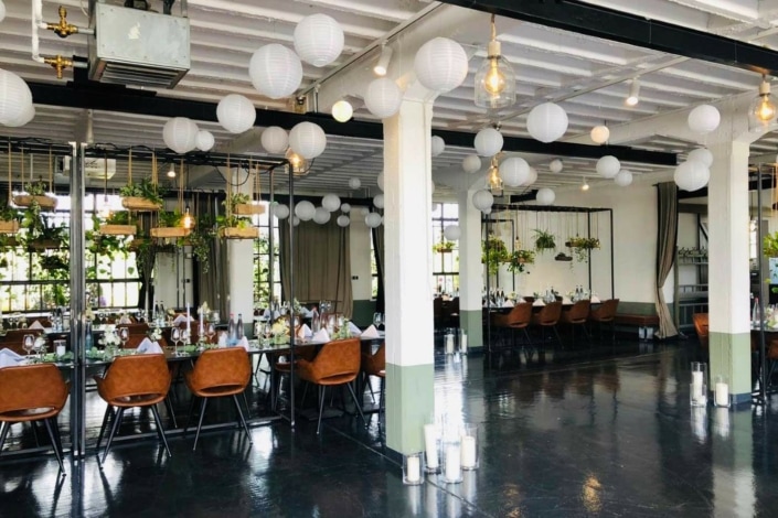 Großzügiger, lichtdurchfluteter Veranstaltungssaal der Reederei Heilbronn mit weißen Lampions, gedeckten Tischen und grünen Akzenten.