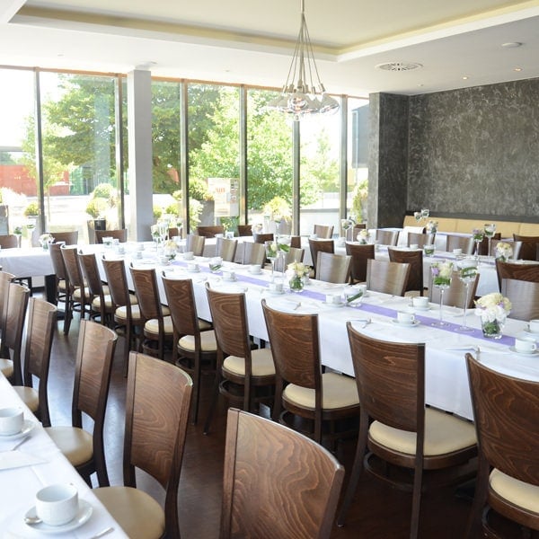 Eleganter Speisesaal, an verschiedenen Stellen für eine formelle Veranstaltung mit Tischen, Stühlen und Geschirr eingerichtet.